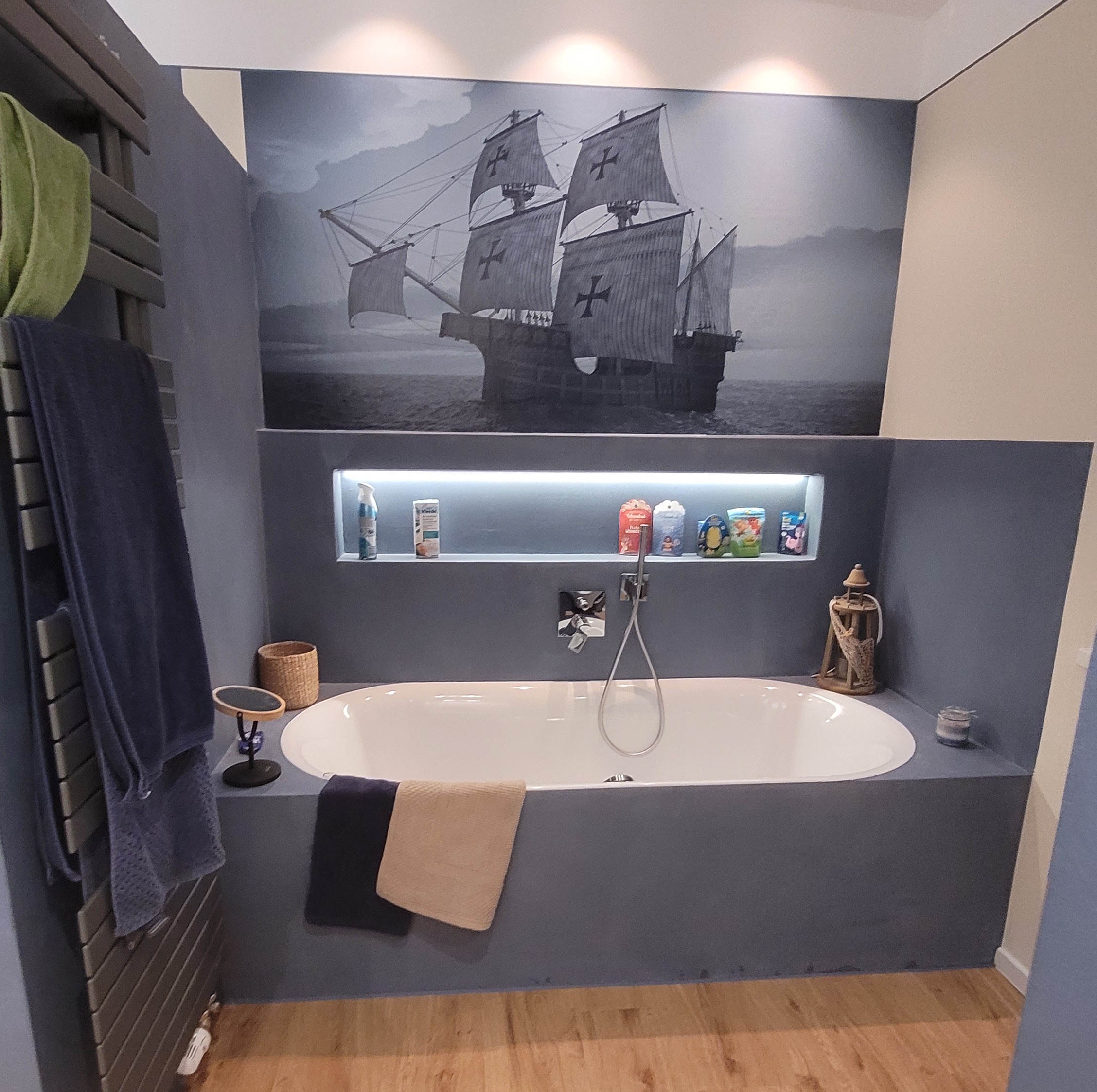 Ein Bad mit einem großen Schiff Bild, einer grauen Badewanne und einem Holzboden